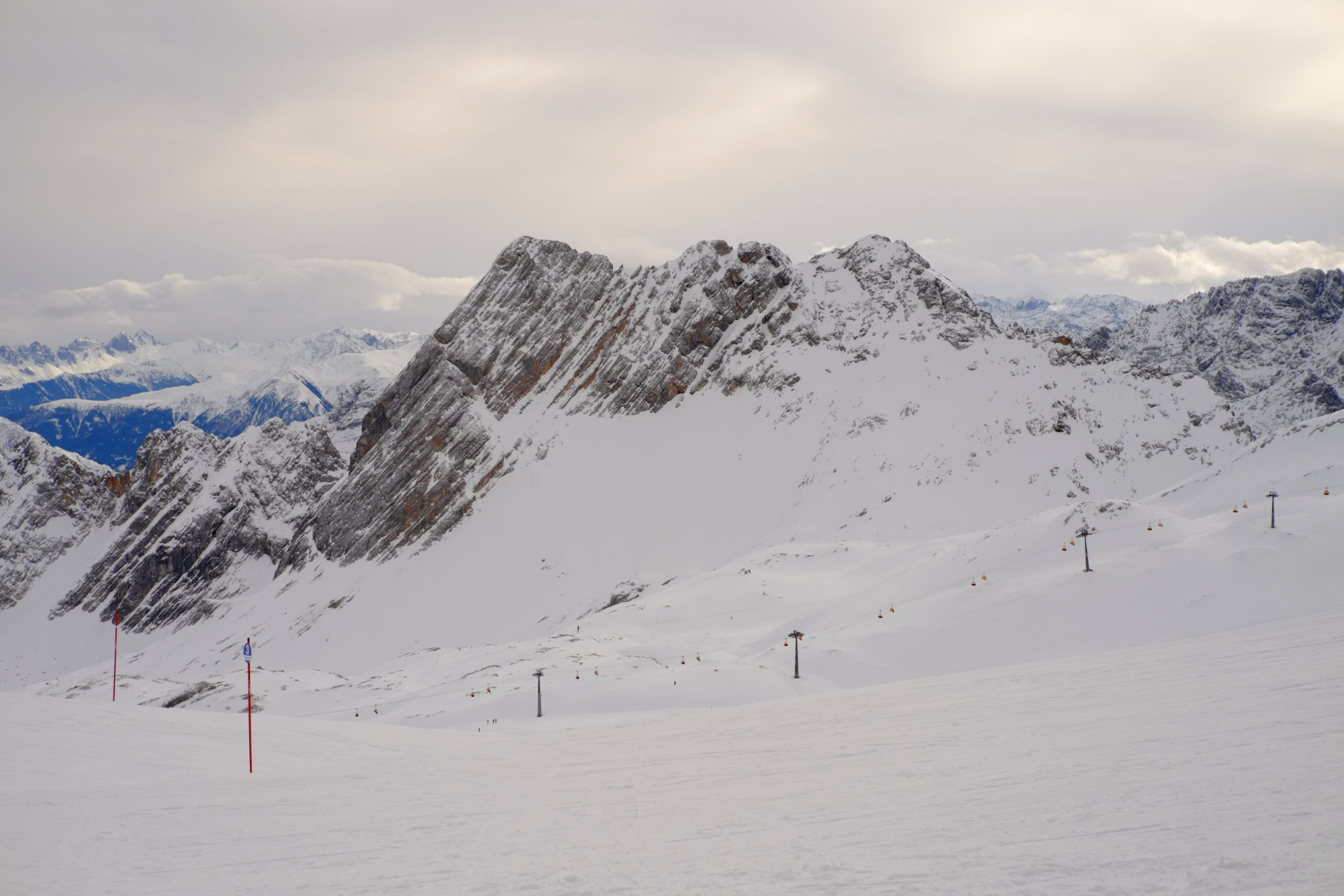 A photo of snowy rocky mountain peaks and snowy slopes for skiing in front of them.