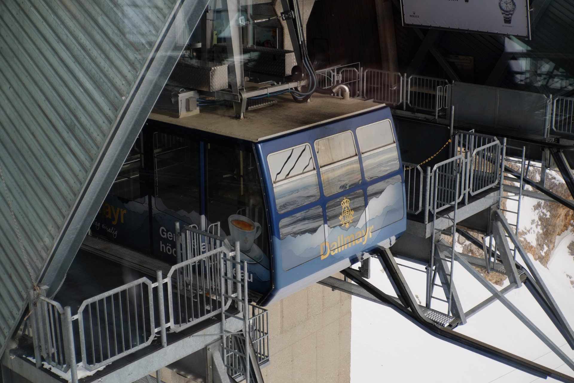 A photo of an empty blue cable car parked at the top station platform.