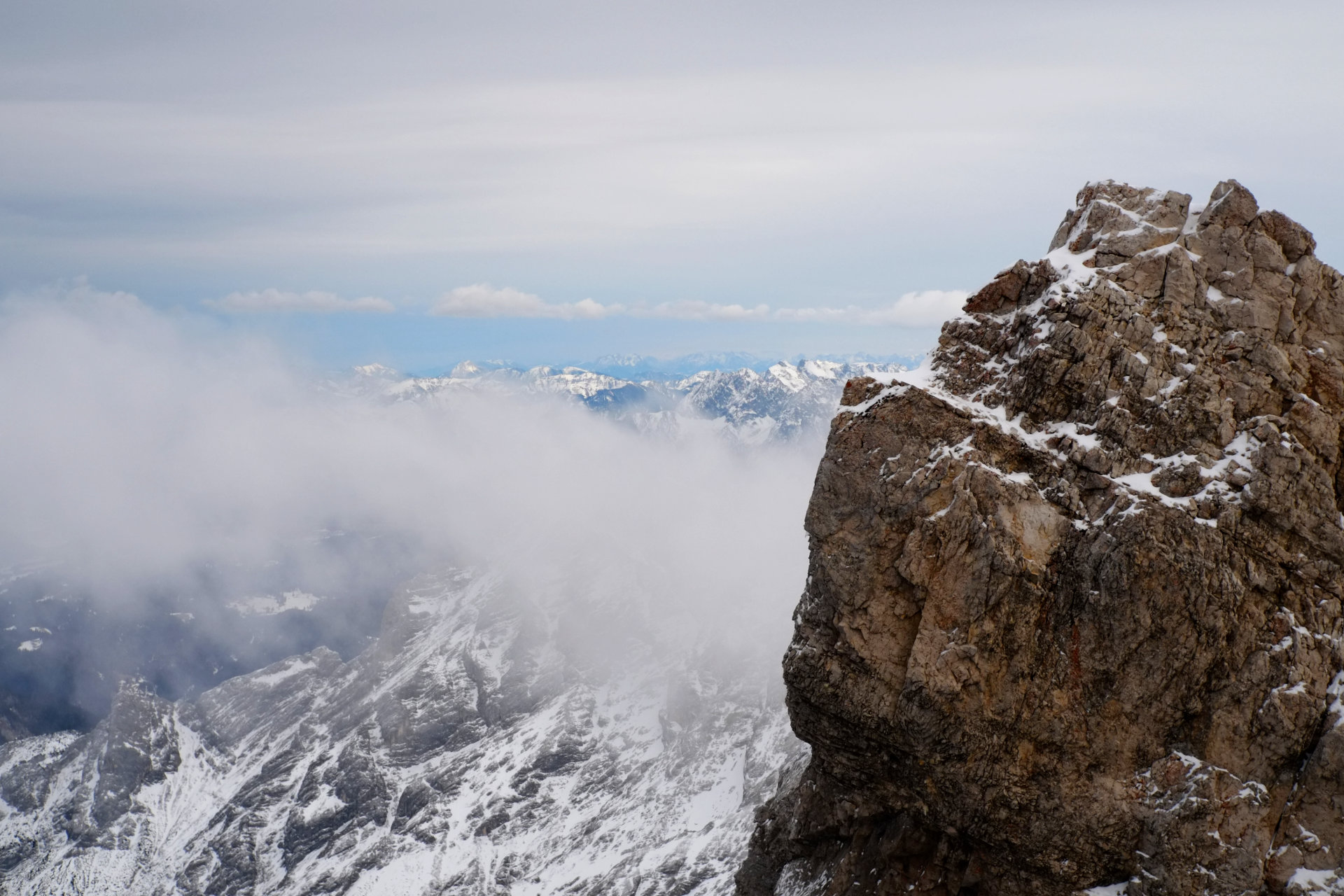A photo of a big brown rock and a small white cloud floating right behind it.