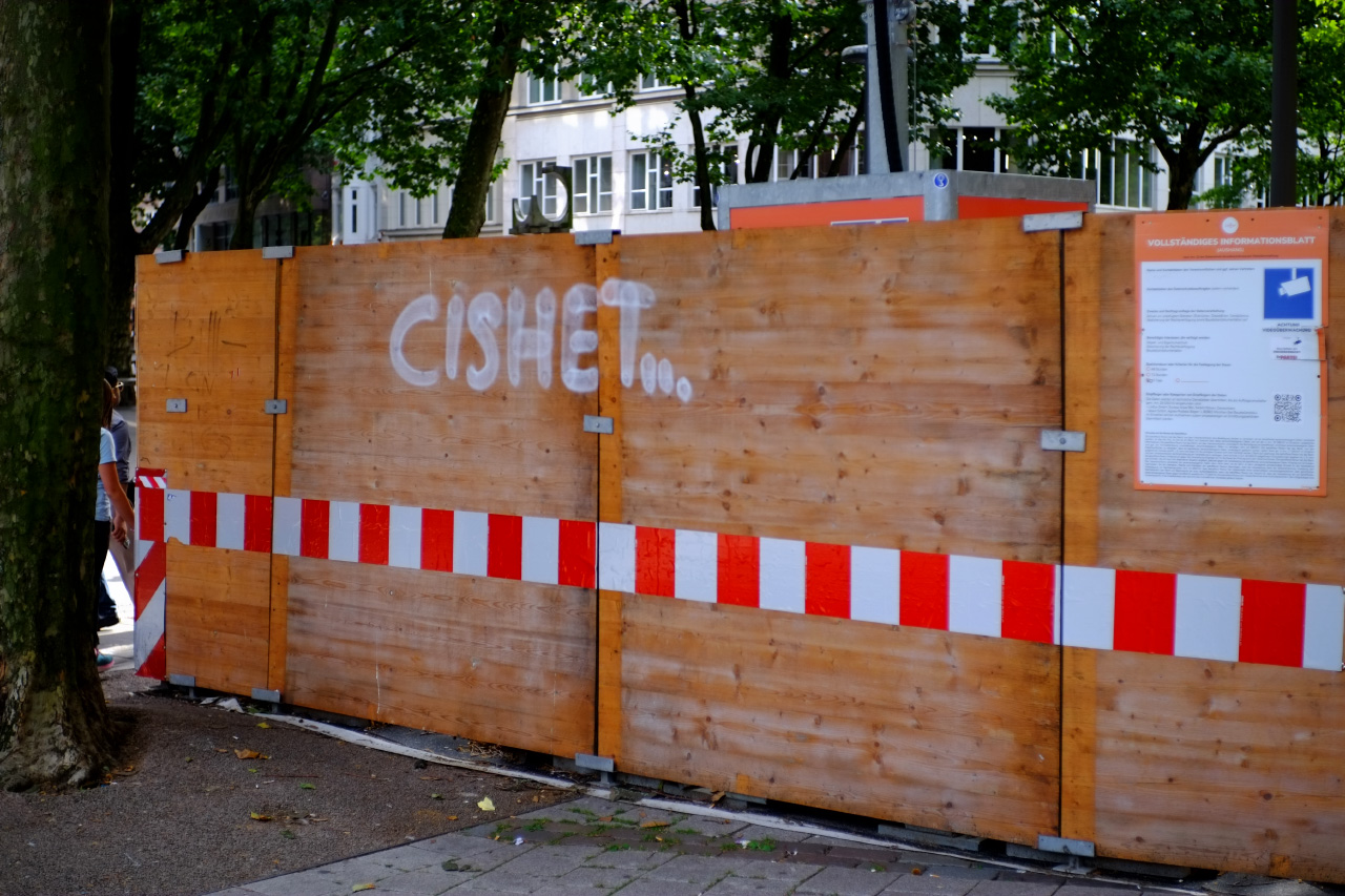 A photo of a wooden plank wall with a word CISHET... written on it