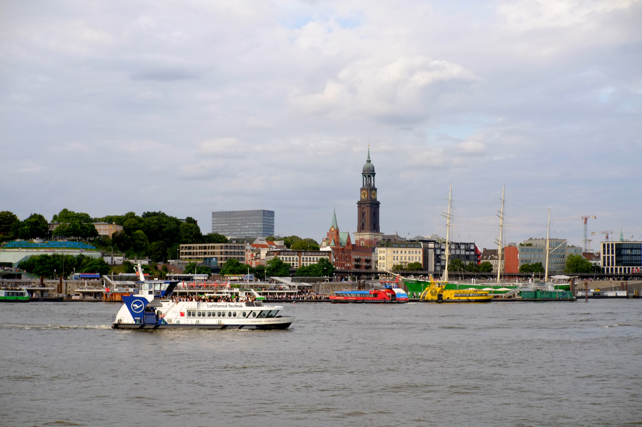 An overview shot of the downtown Hamburg center from the other side of the river, featuring a white tourist boat with a Lufthansa advertisement on it.