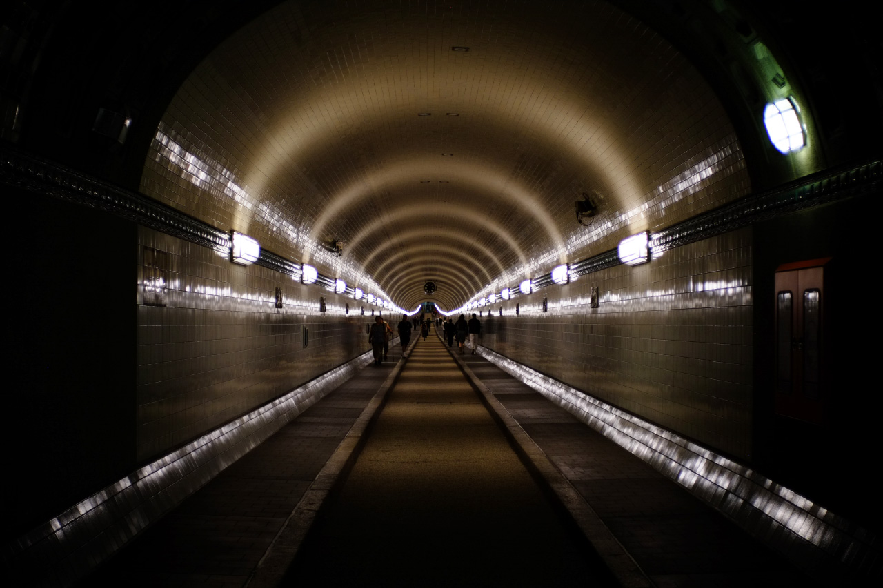 A straight shot from the one start to the end inside Alter Elbtunnel. White light lamps are covering both sides of the tunnel in parallel lines.