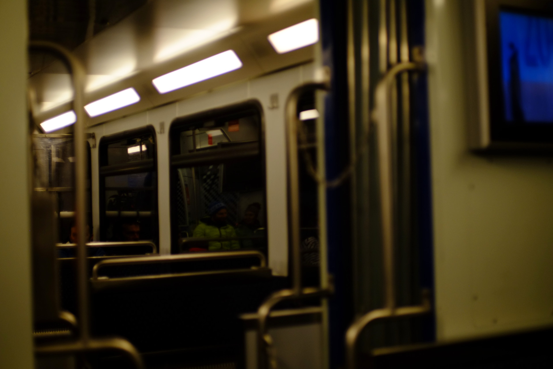 A photo of the inside of the cogtrain car lit with pale yellow lights while moving through a tunnel, most of the seats are empty.