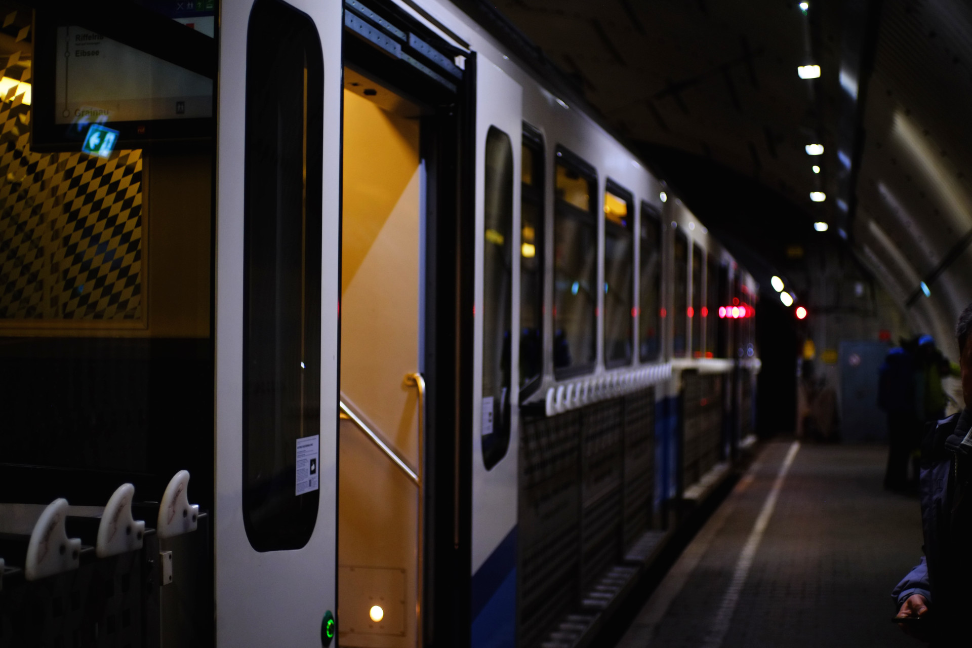 A photo of the second cogtrain car focused on its open door, also featuring the tunnel station platform.