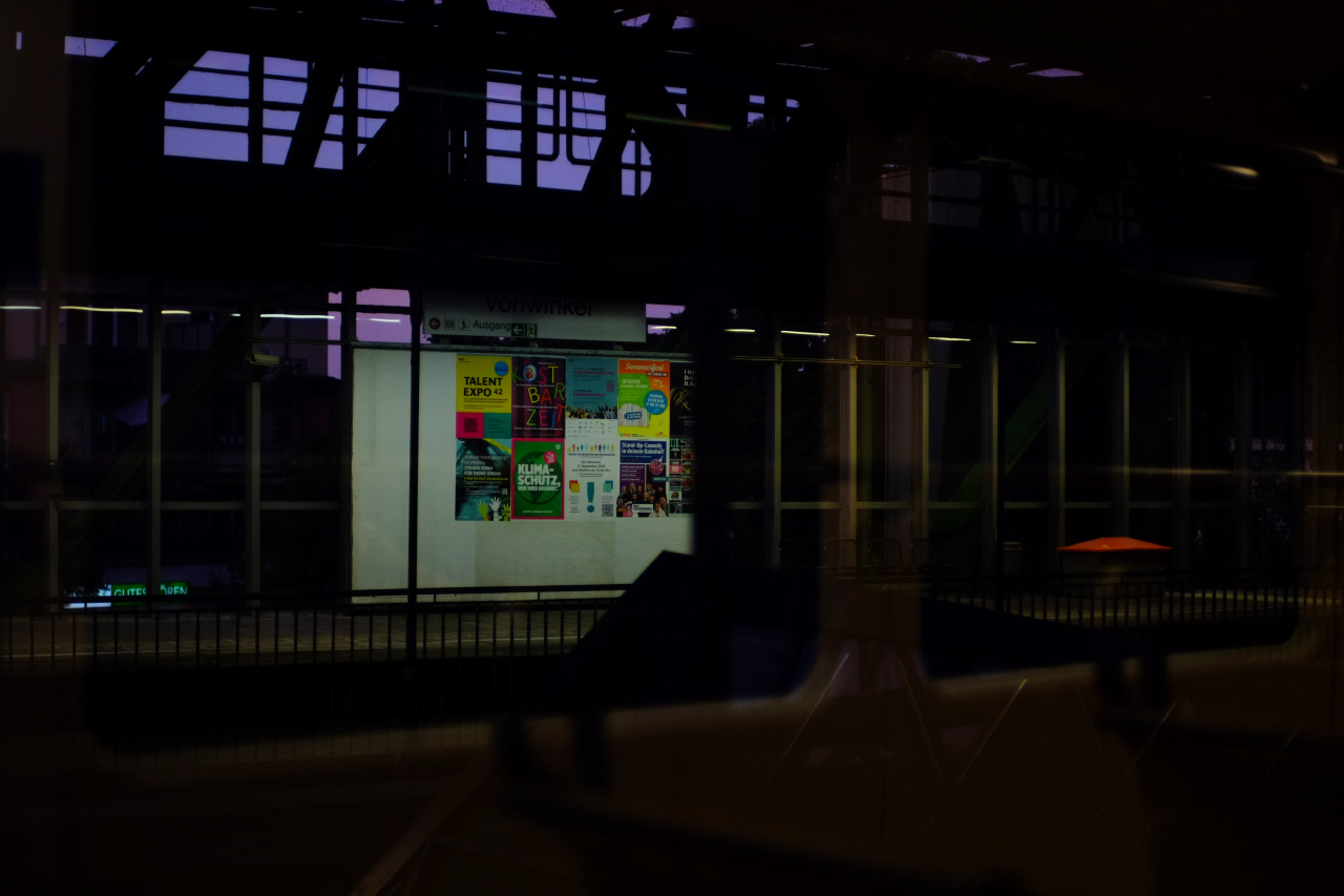 A photo of a late evening suspension railway station through a train car window.