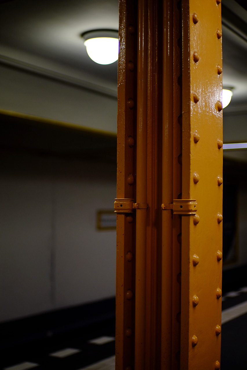 A photo of a big yellow metal bar at an underground metro station that serves as the support for the ceiling.