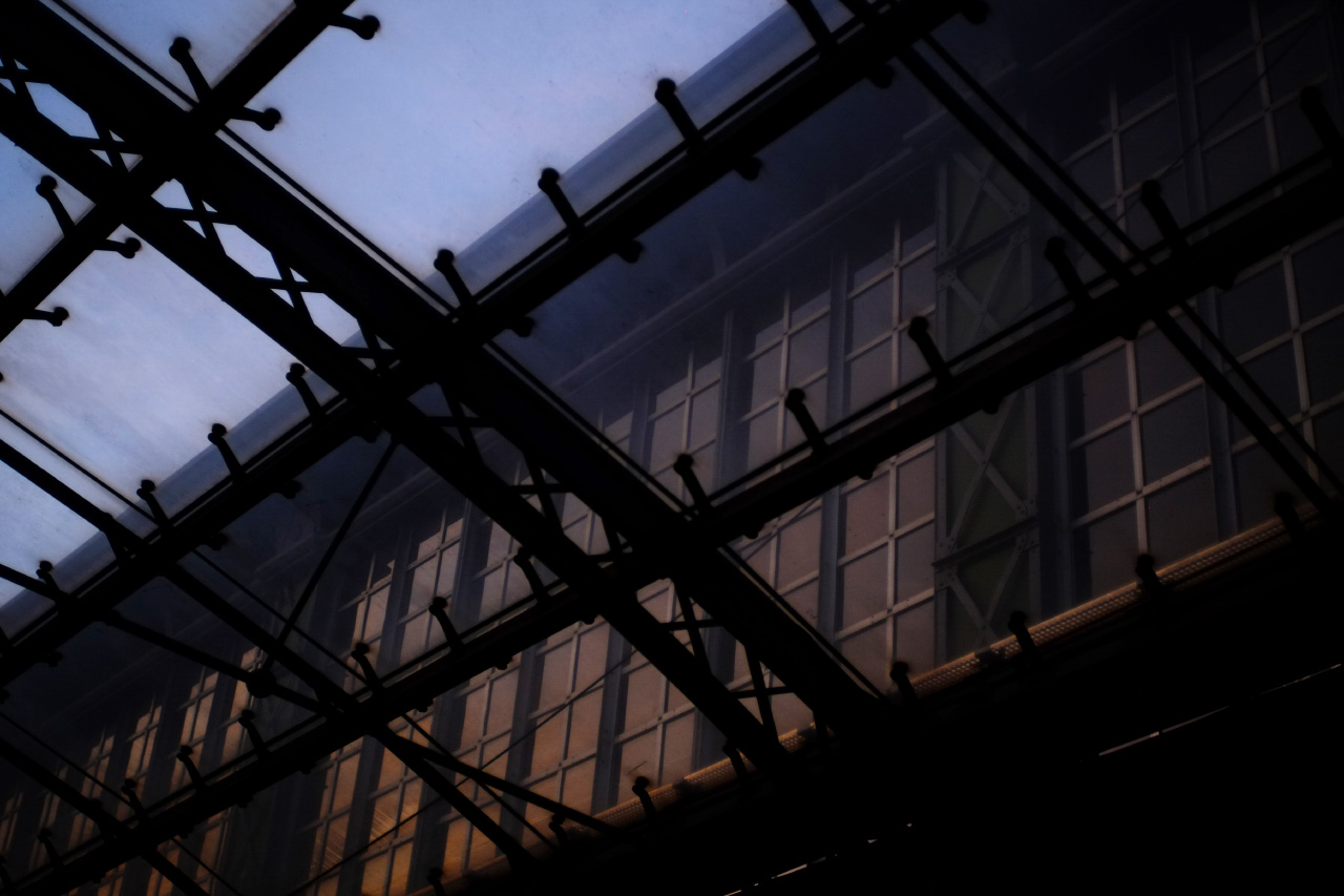 A photo of the main railway station building windows through the glass overhang in front of the building.