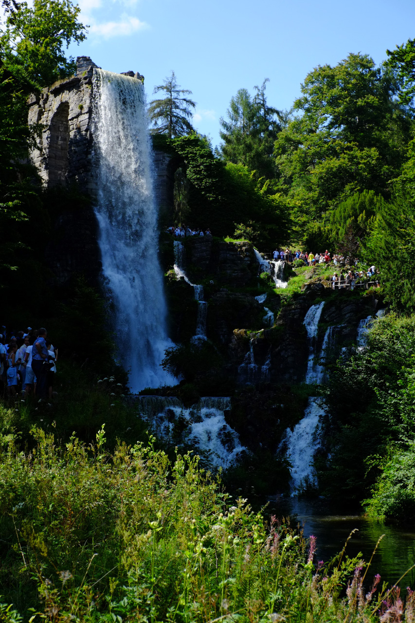A photo of a tall waterfall. The water is falling down from a stone aqueduct.
